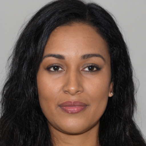 Joyful black young-adult female with long  brown hair and brown eyes