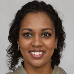 Joyful black young-adult female with long  brown hair and brown eyes