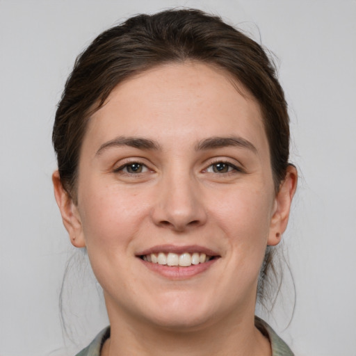 Joyful white young-adult female with medium  brown hair and grey eyes