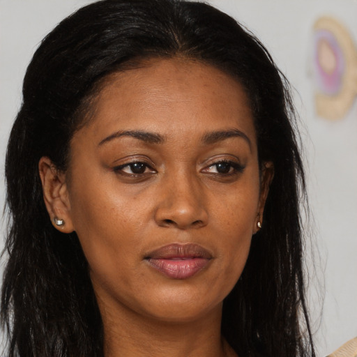 Joyful black young-adult female with long  brown hair and brown eyes