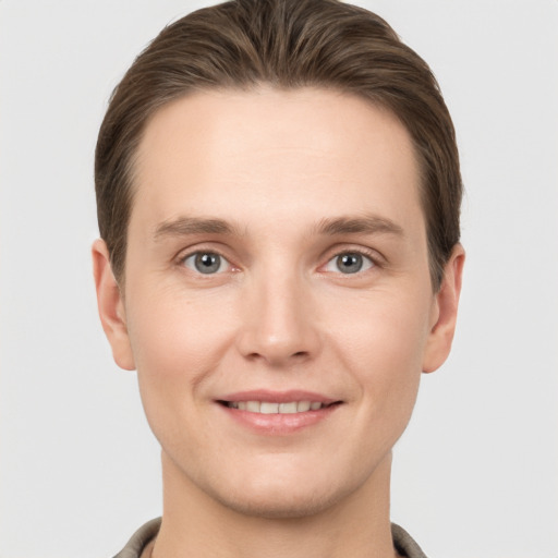 Joyful white young-adult male with short  brown hair and grey eyes