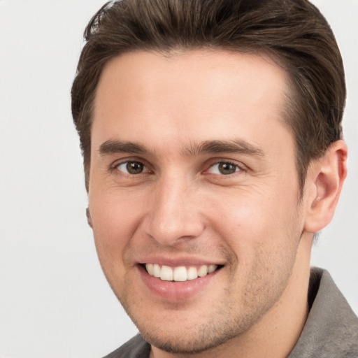 Joyful white young-adult male with short  brown hair and grey eyes