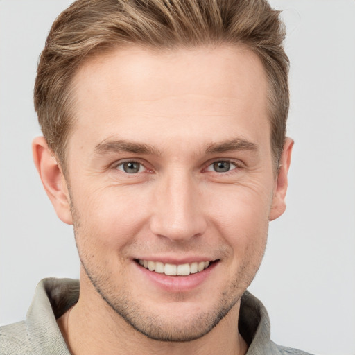 Joyful white young-adult male with short  brown hair and grey eyes