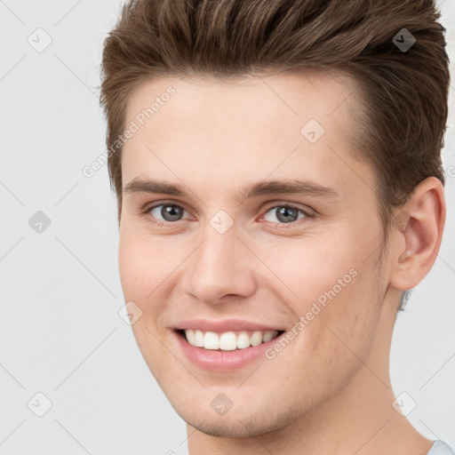 Joyful white young-adult male with short  brown hair and grey eyes