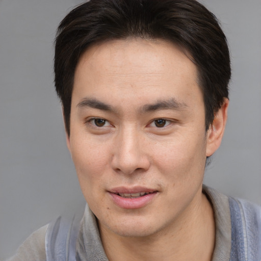 Joyful asian young-adult male with short  brown hair and brown eyes