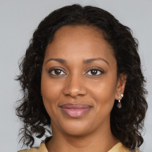 Joyful black young-adult female with long  brown hair and brown eyes