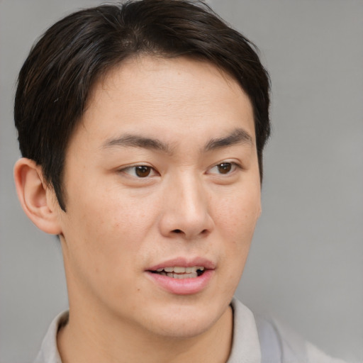Joyful asian young-adult male with short  brown hair and brown eyes