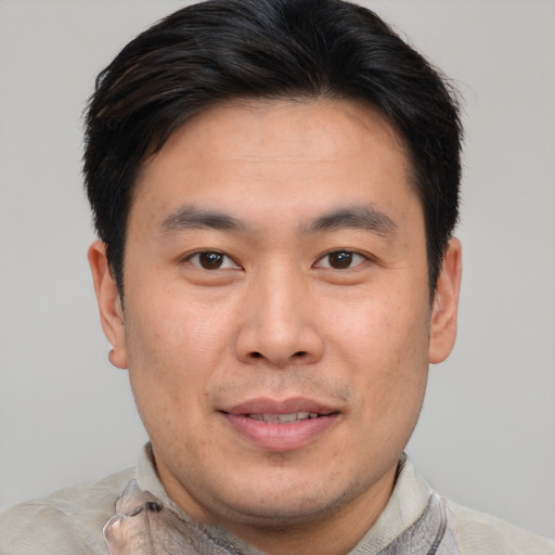 Joyful asian adult male with short  brown hair and brown eyes