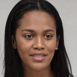 Joyful black young-adult female with long  brown hair and brown eyes