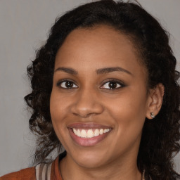 Joyful black young-adult female with long  brown hair and brown eyes