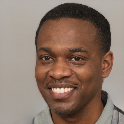 Joyful black young-adult male with short  brown hair and brown eyes