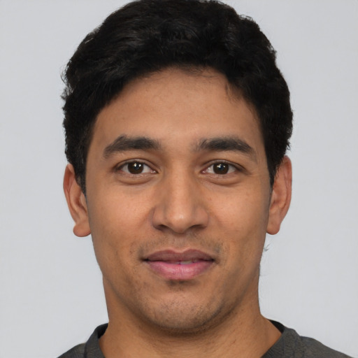 Joyful latino young-adult male with short  black hair and brown eyes