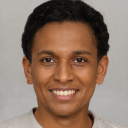Joyful latino young-adult male with short  black hair and brown eyes