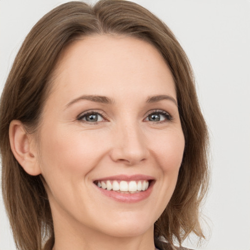 Joyful white young-adult female with medium  brown hair and grey eyes