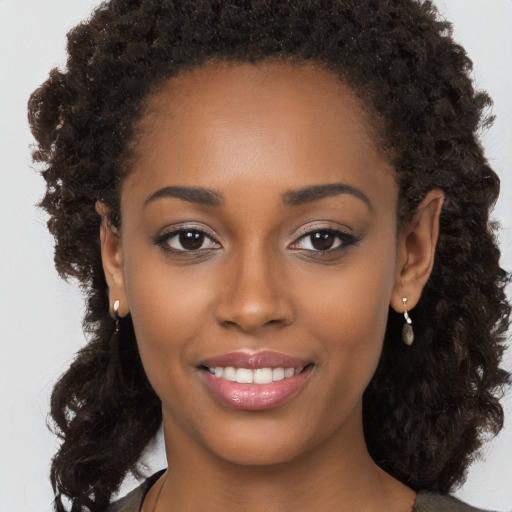 Joyful black young-adult female with long  brown hair and brown eyes