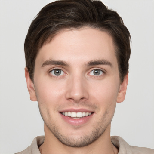 Joyful white young-adult male with short  brown hair and grey eyes