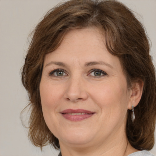 Joyful white adult female with medium  brown hair and green eyes