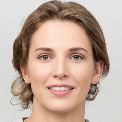 Joyful white young-adult female with medium  brown hair and grey eyes