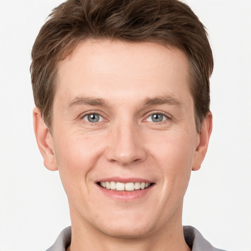 Joyful white young-adult male with short  brown hair and grey eyes