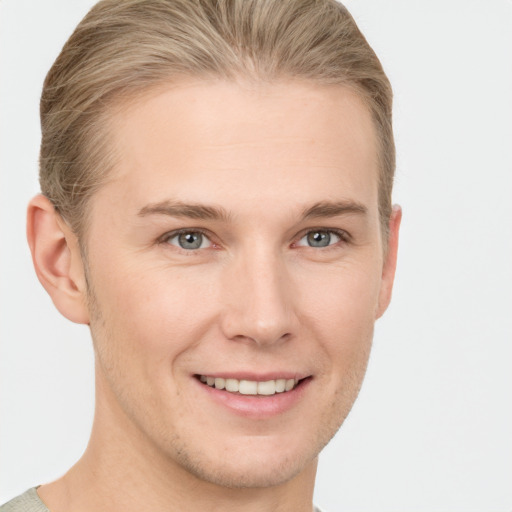 Joyful white young-adult male with short  brown hair and grey eyes