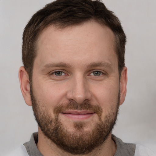 Joyful white young-adult male with short  brown hair and grey eyes