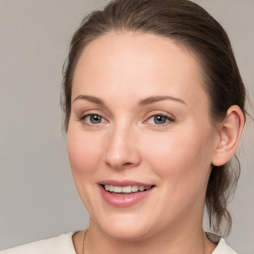 Joyful white young-adult female with medium  brown hair and grey eyes