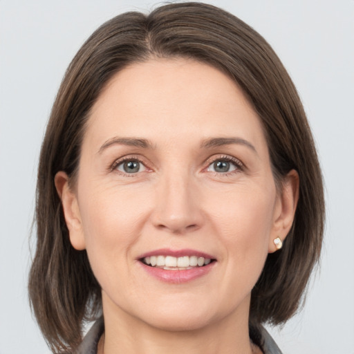 Joyful white adult female with medium  brown hair and grey eyes