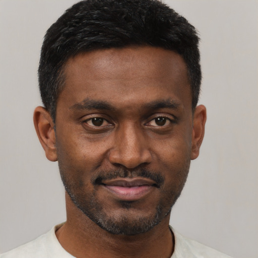 Joyful black young-adult male with short  black hair and brown eyes