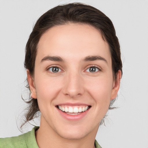 Joyful white young-adult female with medium  brown hair and green eyes