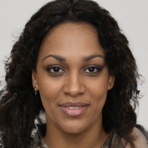 Joyful black young-adult female with long  brown hair and brown eyes