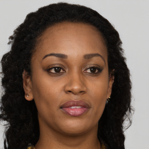 Joyful black young-adult female with long  brown hair and brown eyes