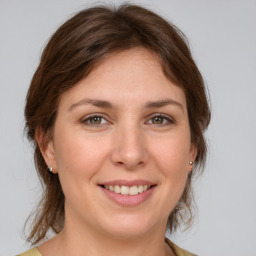 Joyful white young-adult female with medium  brown hair and green eyes