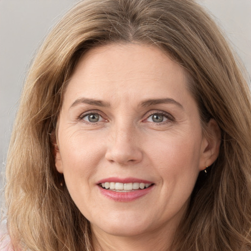 Joyful white adult female with long  brown hair and grey eyes