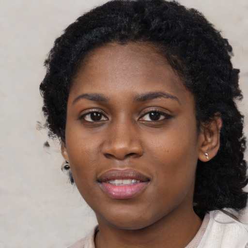 Joyful black young-adult female with long  black hair and brown eyes