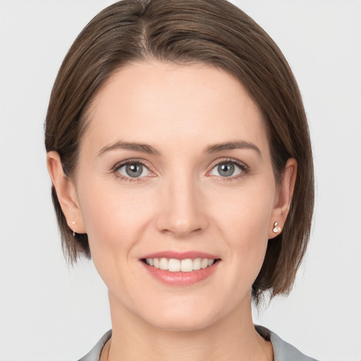 Joyful white young-adult female with medium  brown hair and grey eyes