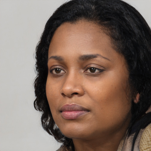 Joyful black young-adult female with long  black hair and brown eyes
