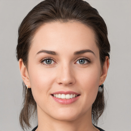 Joyful white young-adult female with medium  brown hair and grey eyes