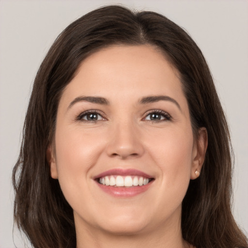 Joyful white young-adult female with long  brown hair and brown eyes