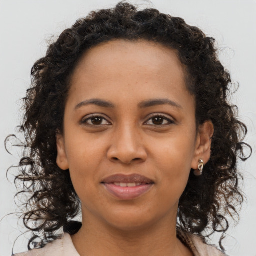Joyful black young-adult female with long  brown hair and brown eyes