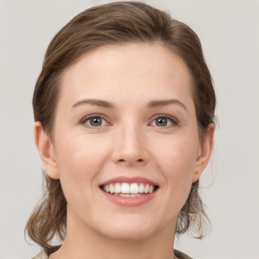 Joyful white young-adult female with medium  brown hair and grey eyes