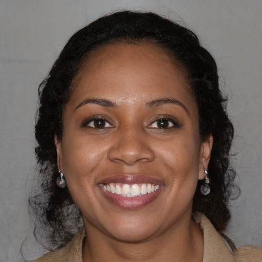 Joyful black young-adult female with long  brown hair and brown eyes
