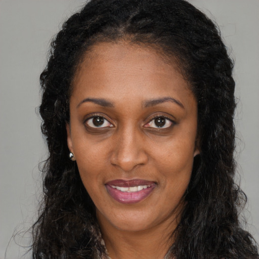 Joyful black young-adult female with long  brown hair and brown eyes