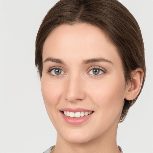 Joyful white young-adult female with medium  brown hair and grey eyes