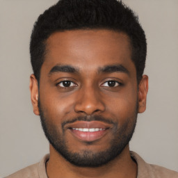 Joyful black young-adult male with short  black hair and brown eyes