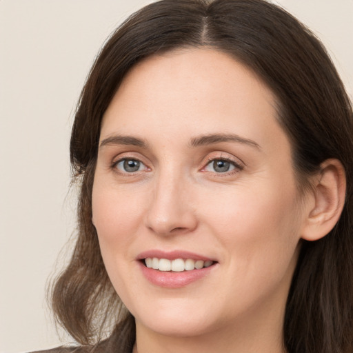 Joyful white young-adult female with long  brown hair and grey eyes