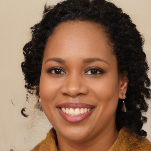 Joyful black young-adult female with long  brown hair and brown eyes