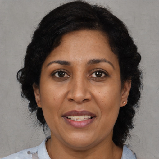 Joyful latino adult female with medium  brown hair and brown eyes