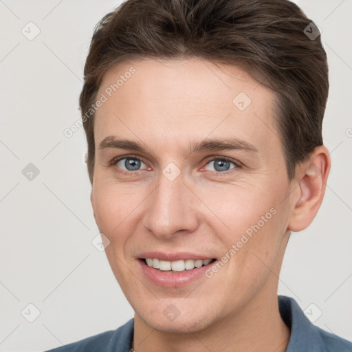 Joyful white young-adult male with short  brown hair and grey eyes