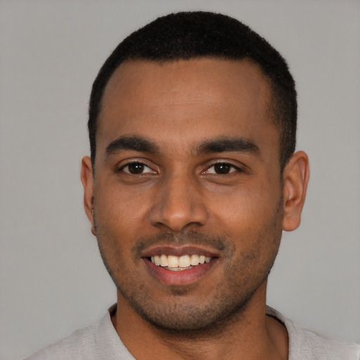 Joyful black young-adult male with short  black hair and brown eyes