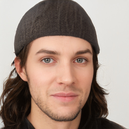 Joyful white young-adult male with long  brown hair and brown eyes